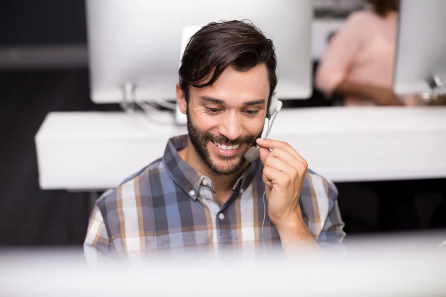 smiling-male-customer-service-executive-talking-headset-desk